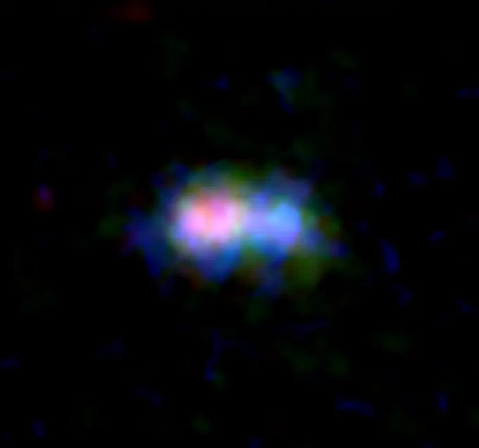 Imagen de la distante galaxia MACS0416_Y1 obtenida por ALMA y el telescopio espacial Hubble (HST). La distribución del polvo y del gas de oxígeno detectados por ALMA se muestra en rojo y verde, respectivamente, mientras que la distribución de las estrellas observadas por el HST se muestra en azul. Créditos: ALMA (ESO/NAOJ/NRAO), telescopio espacial Hubble de la NASA/ESA, Tamura et al.