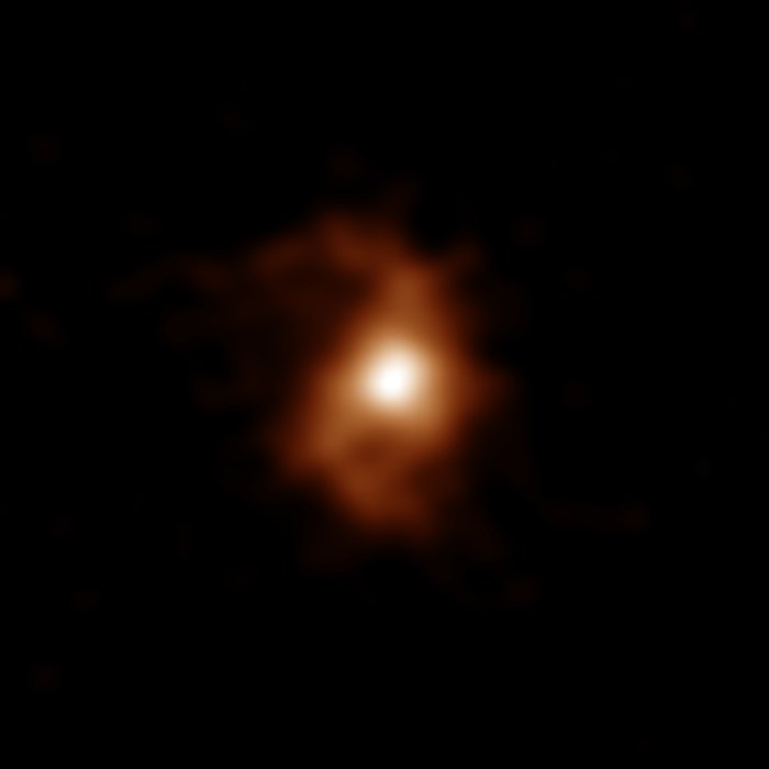 ALMA image of the galaxy BRI 1335-0417 at 12.4 billion years ago. ALMA detected emissions from carbon ions in the galaxy. Spiral arms are visible on both sides of the compact, bright area in the galaxy center. Credit: ALMA (ESO/NAOJ/NRAO), T. Tsukui & S. Iguchi