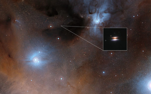 The young star 2MASS J16281370-2431391 lies in the spectacular Rho Ophiuchi star formation region, about 400 light-years from Earth. It is surrounded by a disc of gas and dust — such discs are called protoplanetary discs as they are the early stages in the creation of planetary systems. This particular disc is seen nearly edge-on, and its appearance in visible light pictures has led to its being nicknamed the Flying Saucer. The main image shows part of the Rho Ophiuchi region and a much enlarged close-up infrared view of the Flying Saucer from the NASA/ESA Hubble Space Telescope is shown as an insert.
