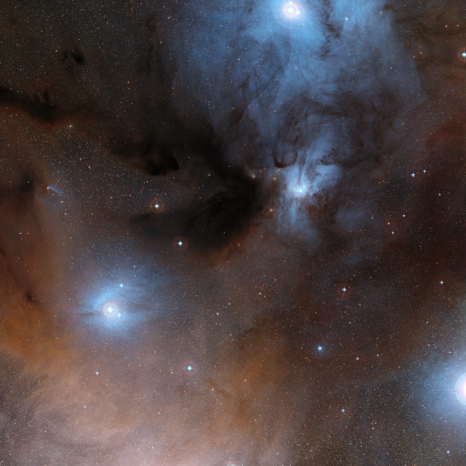 Esta imagen de amplio campo muestra una espectacular zona de nubes oscuras y brillantes que forman parte de una región de formación estelar en la gran constelación de Ofiuco (el portador de la serpiente). Esta fotografía fue creada a partir de imágenes que forman parte del sondeo Digitized Sky Survey 2. Crédito: ESO/Digitized Sky Survey 2 | Agradecimiento: Davide De Martin.