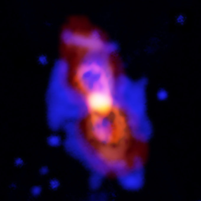 Imagen compuesta de CK Vul, o lo que quedó de una colisión entre dos estrellas. El impacto arrojó moléculas radioactivas al espacio, como se aprecia en la estructura de lóbulo doble naranja en el centro. Esta es una imagen del monofluoruro de aluminio-27 captada por ALMA, pero la escasa versión isotópica del AlF se encuentra en la misma región. La imagen roja y difusa es una imagen de ALMA correspondiente al polvo presente en un área más amplia. El azul corresponde a emisiones ópticas de hidrógeno captadas por el observatorio Gemini. Créditos: ALMA (ESO/NAOJ/NRAO), T. Kamiński y M. Hajduk; Gemini, NOAO/AURA/NSF; NRAO/AUI/NSF, B. Saxton