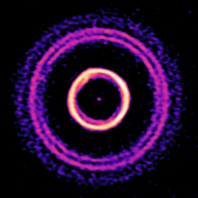 Observación de HD169142 con ALMA que muestra una zona externa compuesta de finos anillos y un surco doble. Estas finas estructuras nunca se habían observado antes en las partes externas de un disco, donde un gran surco separa el entorno protoplanetario en zonas externas e internas. Por otro lado, la imagen de ALMA en alta resolución también revela un brillante anillo interno que muestra señales de haber sido expuesto a perturbaciones dinámicas. Para efectos de comparación se muestra el tamaño del Sistema Solar definido por la órbita de Plutón. Crédito: N. Lira - ALMA (ESO/NAOJ/NRAO); S. Pérez - USACH/UChile