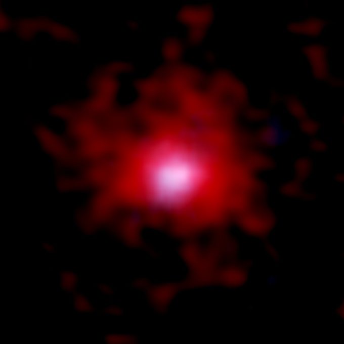 Imagen de una joven galaxia rodeada de una bolsa de carbono gaseoso generada por ALMA y el telescopio espacial Hubble de la NASA/ESA (HST). En rojo se aprecia la distribución del gas de carbono representada a partir de los datos de 18 galaxias obtenidos con ALMA. La distribución estelar fotografiada por el HST se muestra en azul. El tamaño de la imagen es de 3,8 x 3,8 arcosegundos, lo que corresponde a 70.000 x 70.000 años luz, a 12.800 millones de años luz de distancia. Créditos: ALMA (ESO/NAOJ/NRAO), telescopio espacial Hubble de la NASA/ESA, Fujimoto et al.