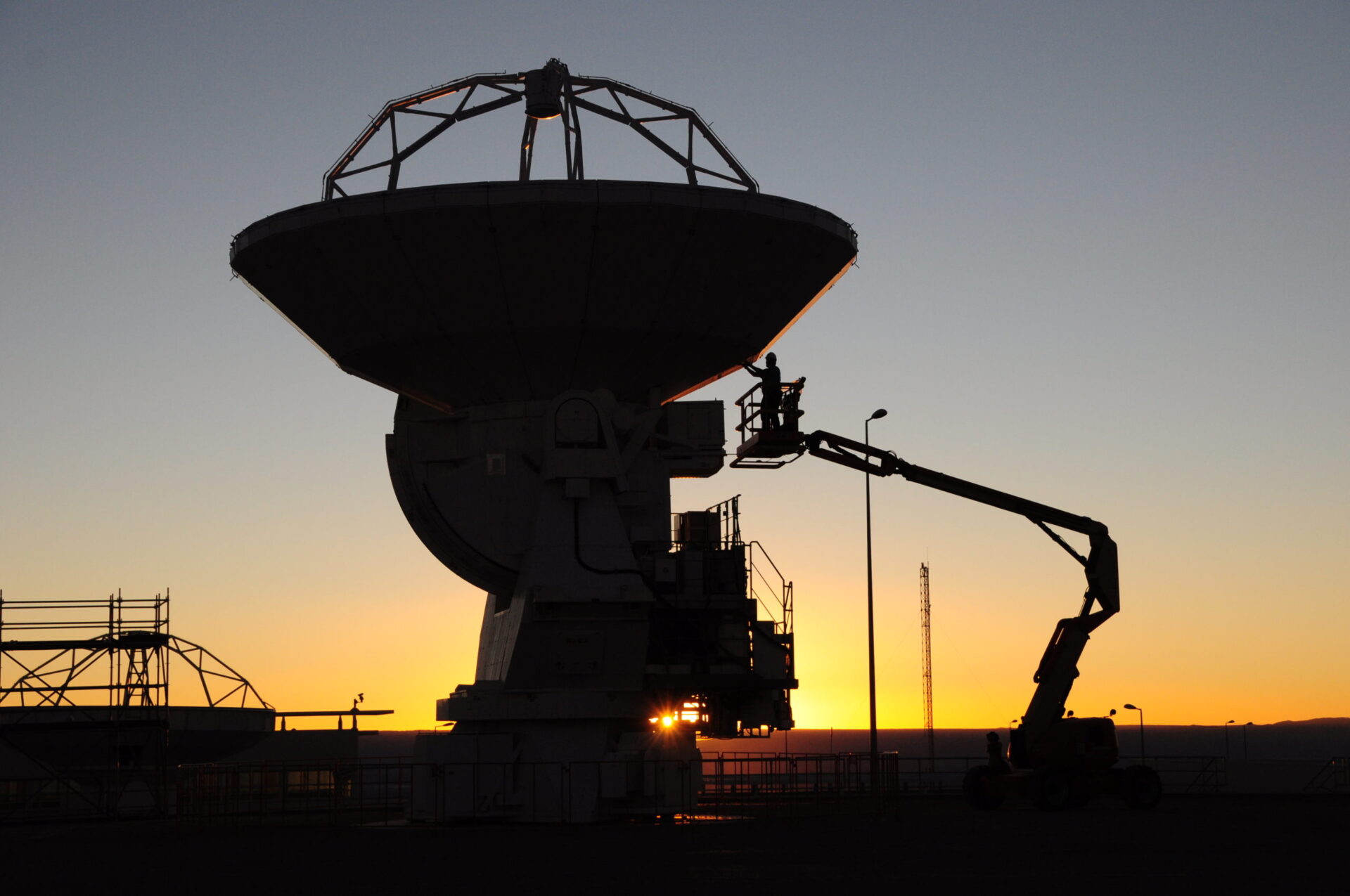 Maintenance technicians, an antenna and a man lift. © ALMA (ESO/NAOJ/NRAO)