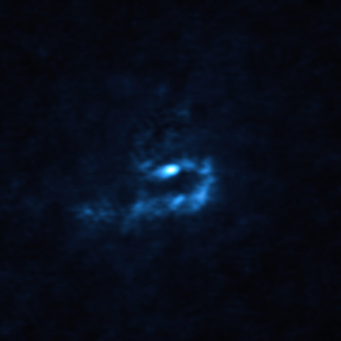 This image of the young star V960 Mon and surrounding dusty material was obtained with the Atacama Large Millimeter/submillimeter Array (ALMA). Large dusty clumps with masses similar to that of planets are visible here as blue blobs. These clumps could contract and collapse via a process known as “gravitational instability” to form giant planets roughly the size of Jupiter. Credit: ALMA (ESO/NAOJ/NRAO)/Weber et al.