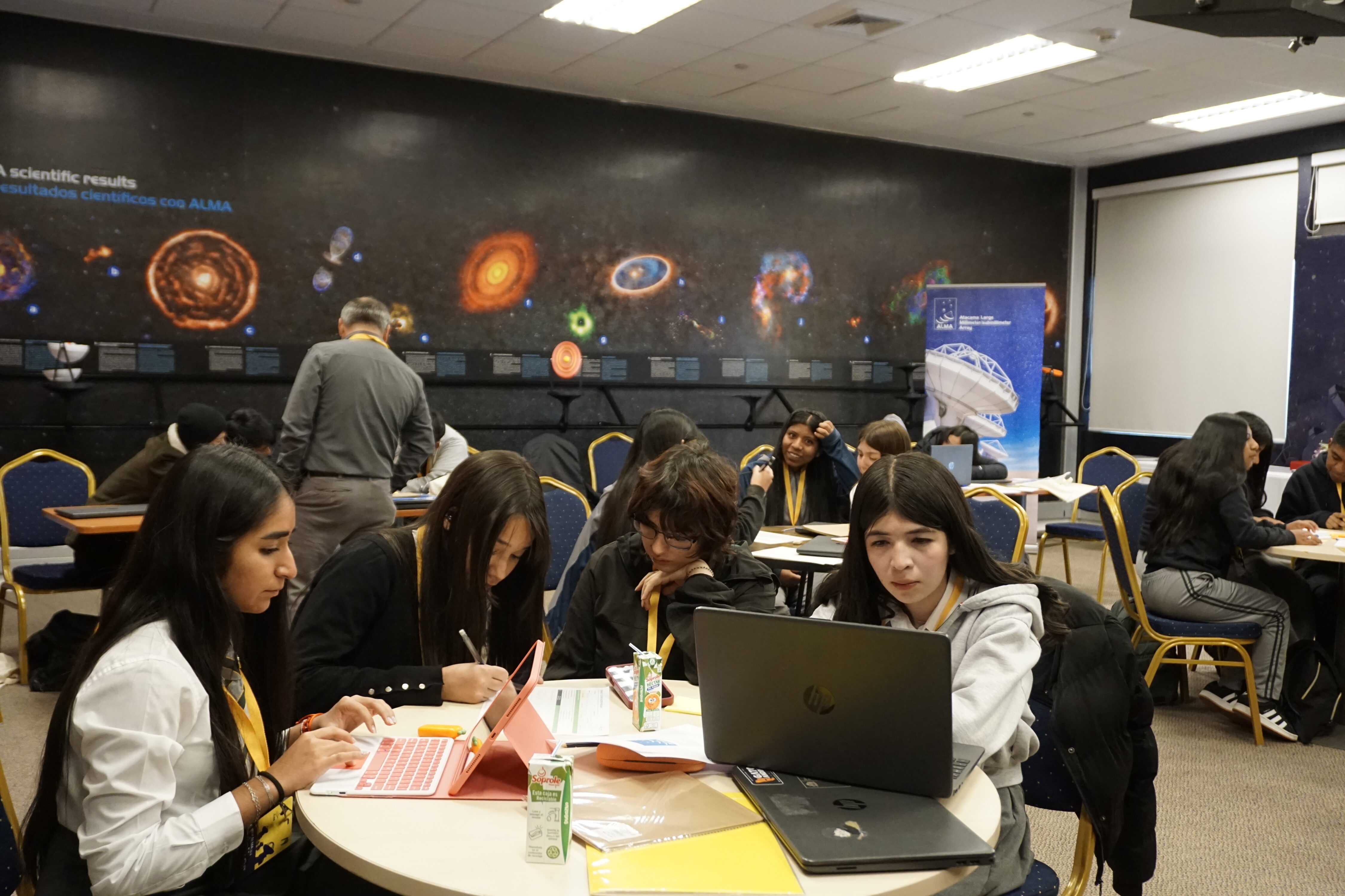 A strong overview of the workshop, showing several teams working simultaneously amid astronomical imagery and institutional graphics.