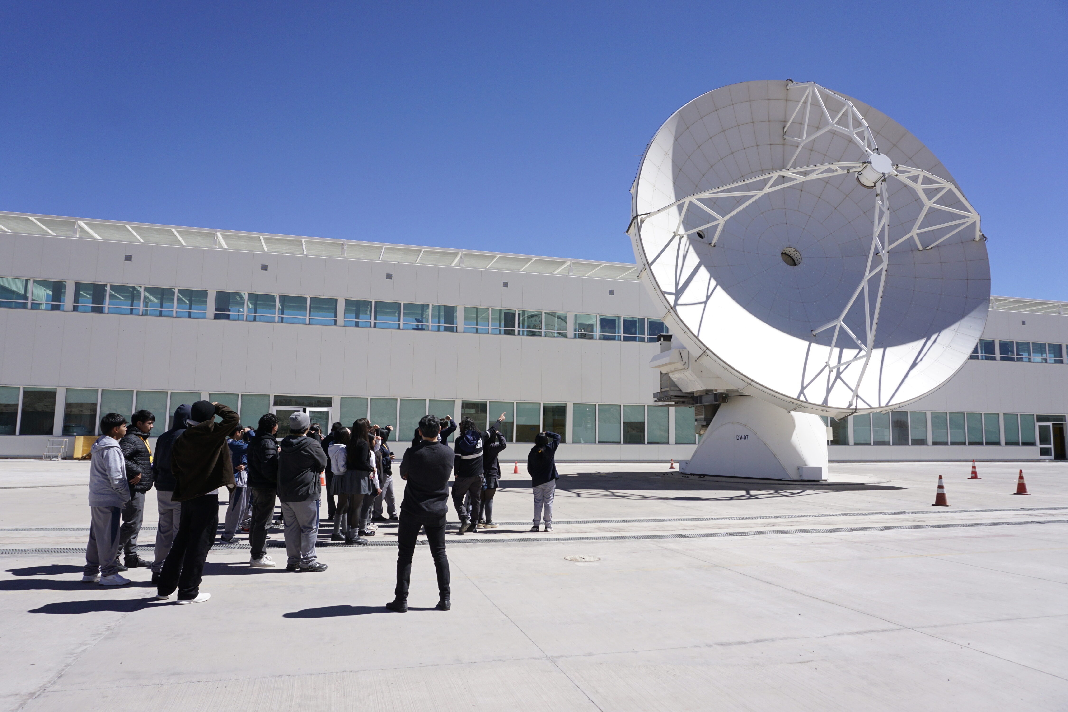Grupo observando una antena de ALMA. Es la mejor toma exterior espontánea y establece claramente el vínculo con el observatorio.